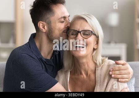 Grown up adult son cuddling and kissing his older mom Stock Photo
