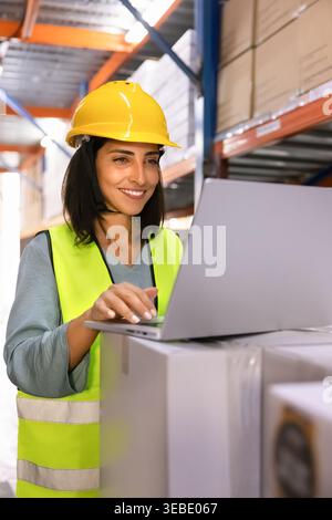 Latina woman logistics worker using laptop in warehouse Stock Photo