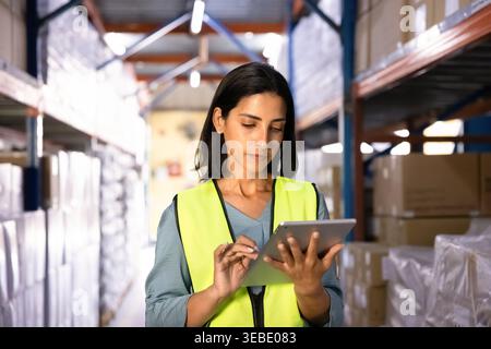 Female warehouse worker working on digital tablet in stockroom Stock Photo