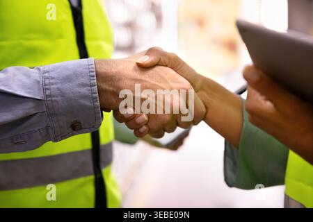 Closeup of two warehouse workers shaking hands Stock Photo