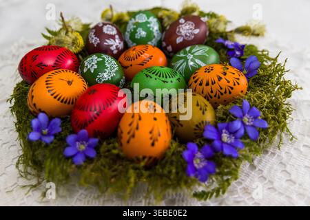 Traditional Lithuanian Easter eggs decorated using the wax-resist technique. Colorful hand-painted eggs with folk ornaments are arranged on moss with Stock Photo