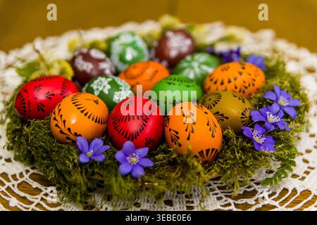 Traditional Lithuanian Easter eggs decorated using the wax-resist technique. Colorful hand-painted eggs with folk ornaments are arranged on moss with Stock Photo