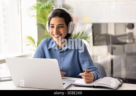Smiling businesswoman on headphones working or studying at laptop Stock Photo