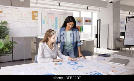 Two young women engaged in collaborative work in modern office Stock Photo