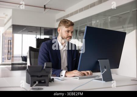 Young businessman working on desktop computer in office Stock Photo