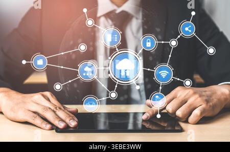 A businessman in a suit interacts with a tablet, surrounded by cloud computing icons, symbolizing modern technology and network connectivity solutions Stock Photo