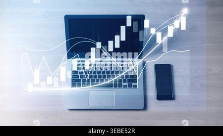 A sleek laptop displaying financial charts alongside a smartphone on a wooden table, illustrating modern stock market analysis and investment Stock Photo