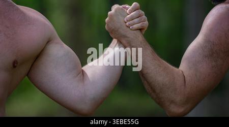 Rivalry between men shows muscular power. Rivalry creates strong arm wrestling challenge. Two hands hold rivalry grip. Physical contest proves rivalry Stock Photo