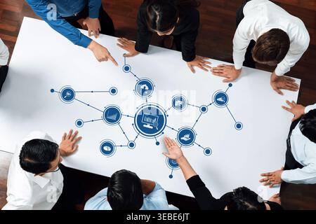 A diverse group of professionals engaged in a brainstorming meeting, analyzing data insights through a digital graphic visualization on a large table Stock Photo