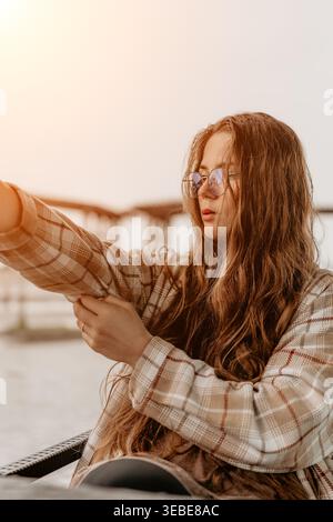 Woman plaid jacket eyeglasses adjusting her sleeve while sitting outdoors during a golden hour sunset Stock Photo