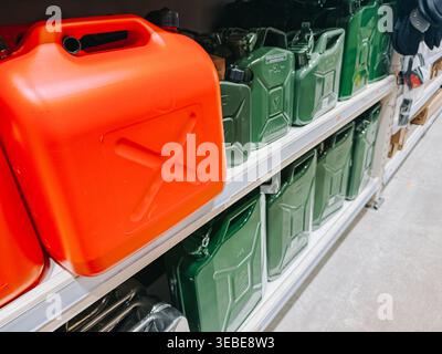 Valmiera, Latvia - April 22, 2026:Close-up of fuel jerry cans displayed on a retail shelf in a hardware store aisle. Bright red and green containers e Stock Photo