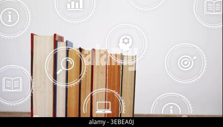 Displaying hardback books showing worn pages standing on wood desk, with white learning icons Stock Photo