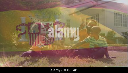 Blowing family wearing short sleeves sitting on front yard, reaching for soap bubbles with wand Stock Photo