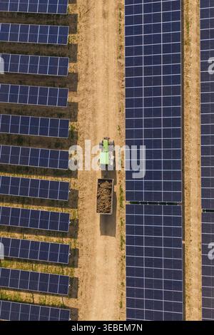 Aerial view of solar panels arranged in rows across a lush green field ...