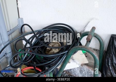 Water hose for irrigation is rolled into a ring. New long hose on concrete background top view Stock Photo