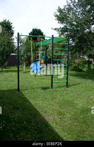 Blue plastic swing in green sunny garden Summer grass Stock Photo