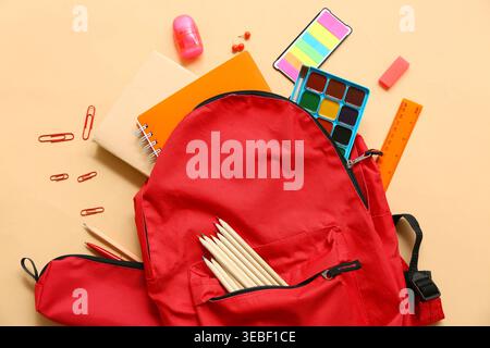School backpack with different stationery supplies on beige background Stock Photo