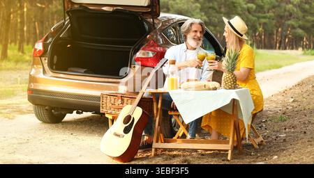 Happy mature couple having picnic in forest Stock Photo