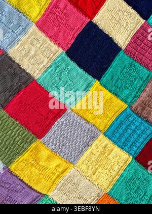 Pattern of squares on a knitted blanket using different coloured wool. Backgrounds. Stock Photo
