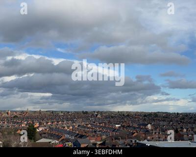 Suburban brick rooftops under dramatic layered clouds and blue sky Stock Photo