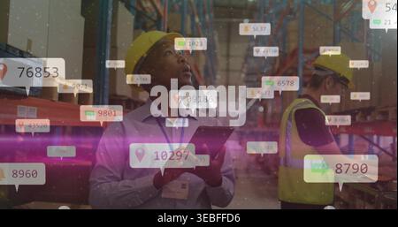 Checking lead in yellow hardhat holding tablet at warehouse, worker using scanner in hivis, AR tags Stock Photo
