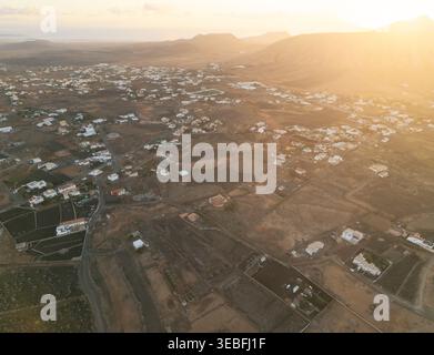 Aerial view of the volcanic landscape and traditional white houses under a warm golden sunset in Lanzarote, Canarias, Spain. Stock Photo