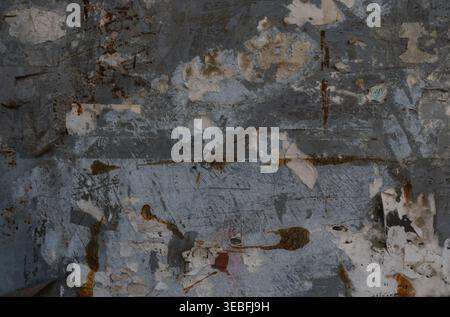 Close-up of a heavily weathered metal surface with peeling paint and rust stains. The distressed texture reveals layers of old paint and corrosion. Stock Photo