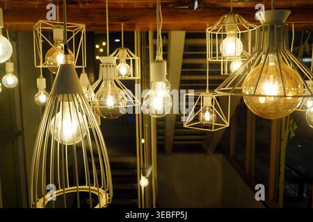 Group of decorative industrial pendant lights with glowing Edison bulbs, stylish modern interior lighting for cafe and home decor. Stock Photo