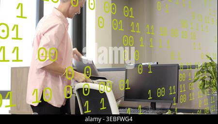 Holding office worker in light pink shirt placing laptop on chair at cubicle desk, binary overlay Stock Photo