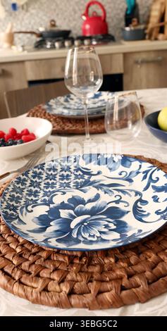 Mediterranean Floral Ceramic Plate on Natural Fiber Placemat. Sustainable table setting trend combines organic textures with traditional blue white Stock Photo