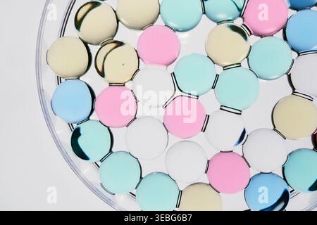 Circular droplets floating on clear liquid forming soft pastel abstract background Stock Photo