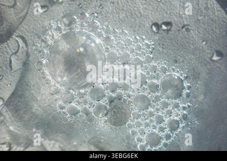 Close up of shiny soap bubbles creating an abstract pattern on grey liquid surface Stock Photo