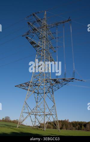 Powerful electricity pylon against a clear blue sky. Steel backbone of infrastructure symbolizing industrial strength and reliable energy supply. Stock Photo