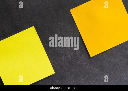 Horizontal image of two angled blank sticky notes, one yellow and one orange stuck on a grey stone like surface Stock Photo