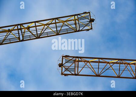Industrial Yellow Tower Crane Jibs Against a Blue Sky Background Stock Photo