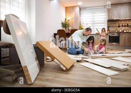 Family bonding while assembling furniture in a cozy home environment Stock Photo
