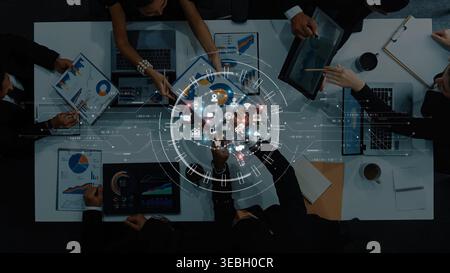 A top-down view of a business meeting, showcasing teamwork and technology. The image features data analysis, charts, and interactive digital elements Stock Photo