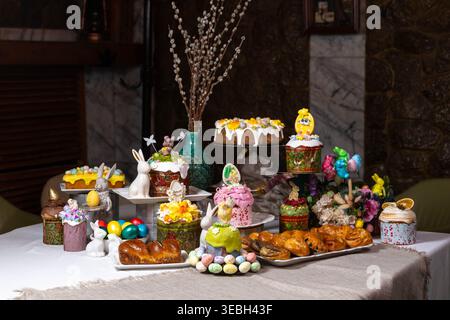 Festive Easter table with traditional cakes, dyed eggs, and decorative bunnies. Stock Photo