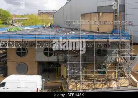 Roofing workers in high-vis undertaking roof repair & maintenance works on the roof of the Anvil concert hall theatre, Basingstoke, UK Stock Photo