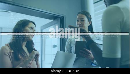 Discussing three women in workwear holding laptop, tablet and papers near glass door, code overlay Stock Photo