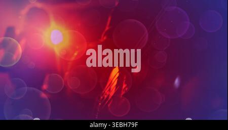 Glowing ambiguous silhouette and overlapping bokeh filling dark studio, with warm orange-red light Stock Photo
