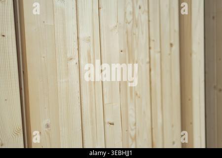 Close-up of vertical wooden wall panels with natural grain. Decorative cladding used in interiors, showcasing clean lines and warm organic texture. Stock Photo