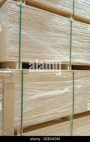 Close-up of stacked wooden planks secured with straps. Construction timber stored for transport or sale, showing natural texture and grain of Stock Photo