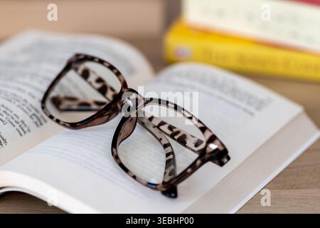 A closeup of a pair of folded reading glasses on an open book. Stock Photo