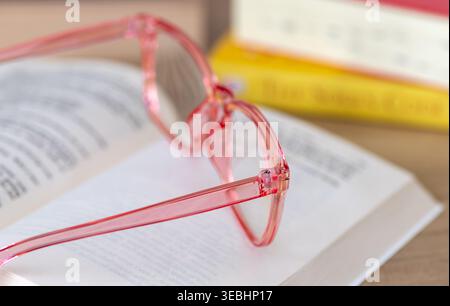 A close up of a pair of pink reading glasses on an open book. A learning concept. Stock Photo
