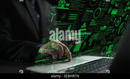 A businessman analyzes green energy data on a laptop screen, displaying charts and graphs that highlight sustainable technology and innovation in a Stock Photo