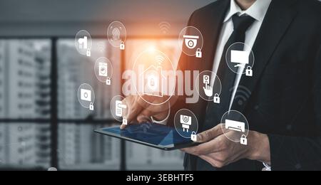 Businessman interacts with tablet, showcasing digital icons of home security and smart technology systems, representing modern cybersecurity and Stock Photo