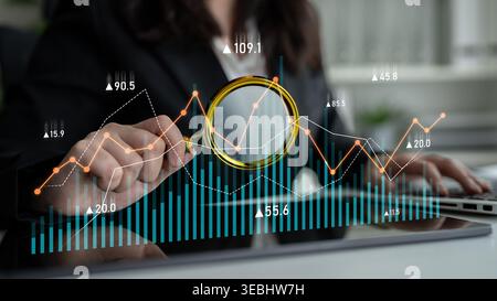 Business professional focuses on data analysis with financial graphs and charts, utilizing a magnifying glass for detailed insights and informed Stock Photo