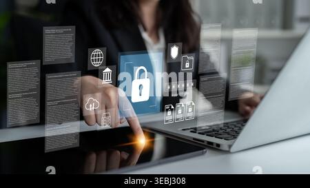 A professional woman engages with a laptop, surrounded by digital graphics representing security and data protection in a modern workspace Stock Photo