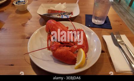 Delicious Lobster Dinner with Lemon Wedge and Water Glass on Wooden Table Stock Photo
